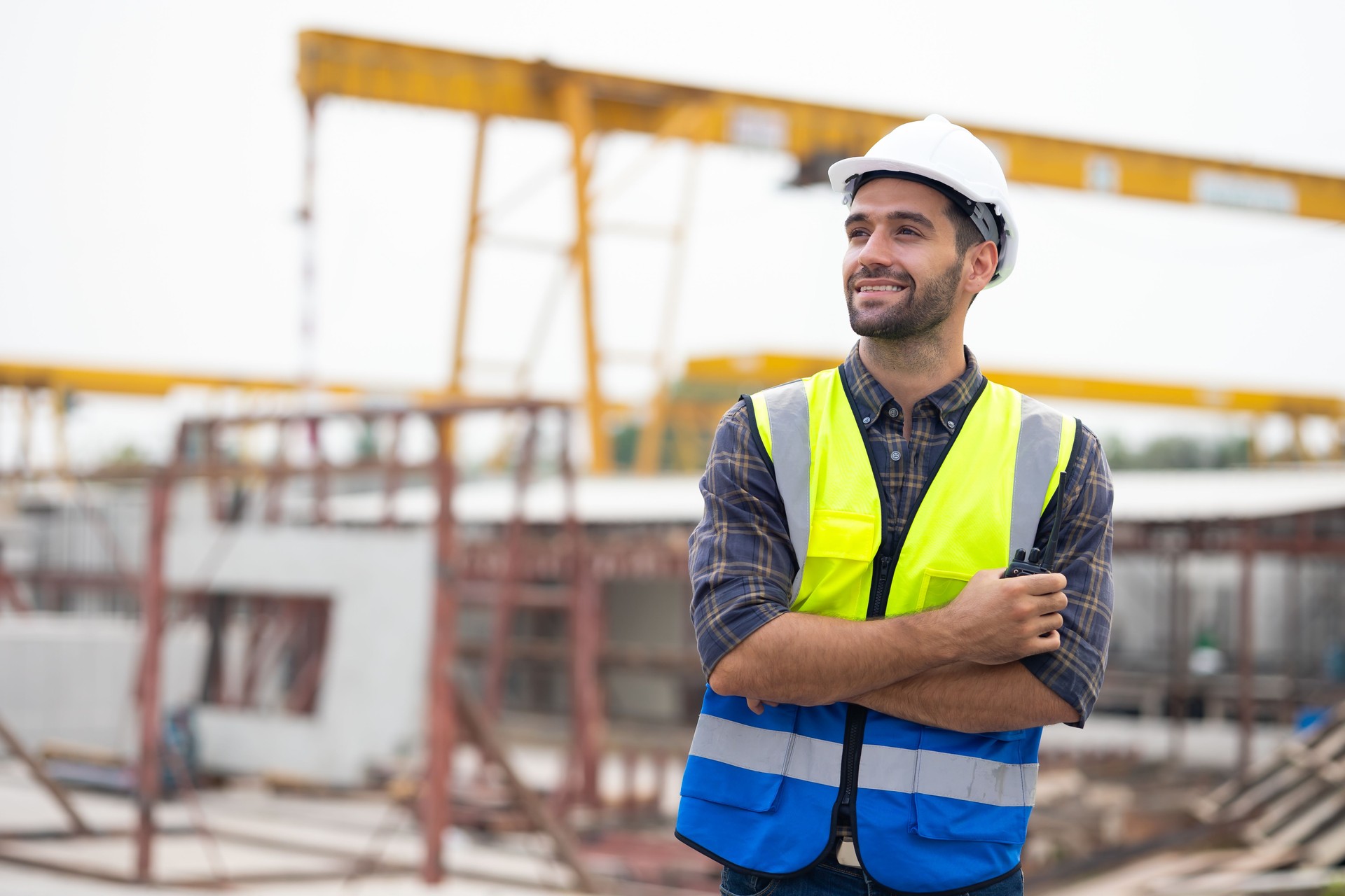 Portrait building and construction worker, Hiapanic latin male wearing safety hard hat helmet standing with arms crossed at construction site and looking at camera